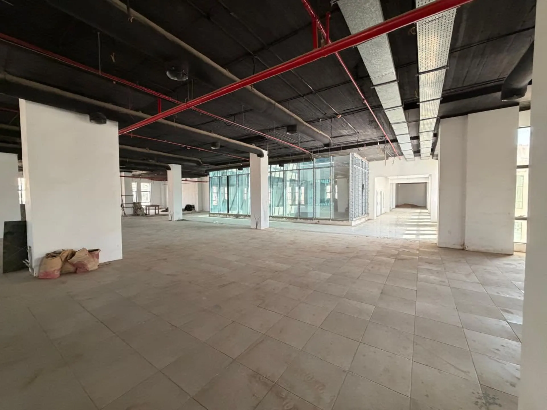 Open office floor with columns and a glass-fronted wing in an administrative office for rent in First Settlement
