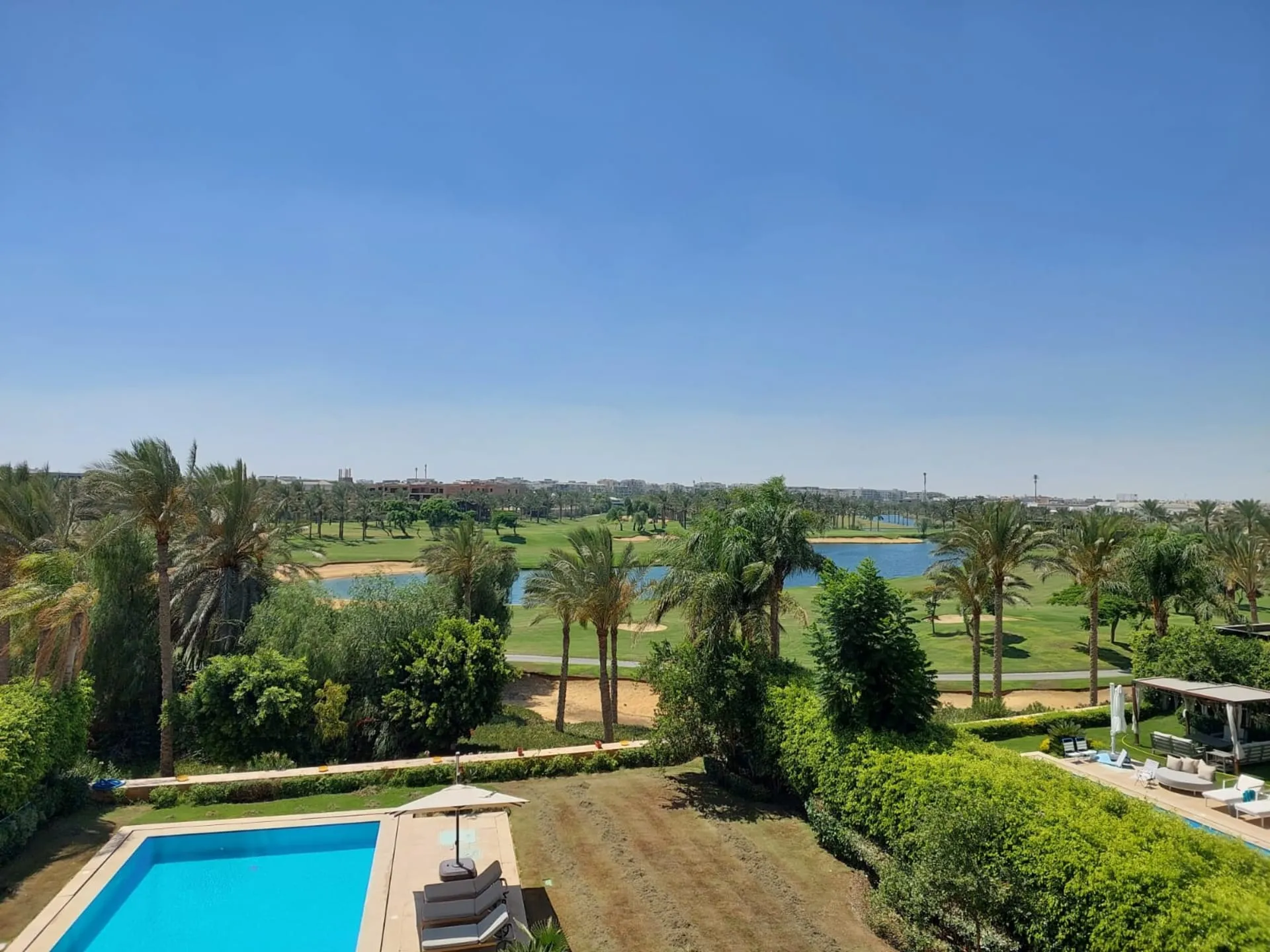 View from a furnished apartment in Katameya Dunes, New Cairo over a pool, palm trees and the golf course lake