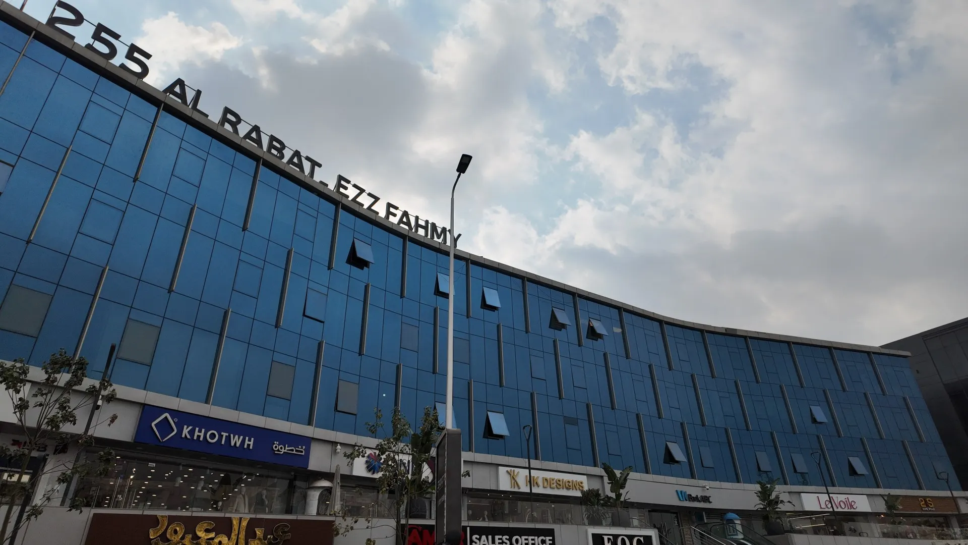 Curved blue-glass office building with shops on the ground floor in New Cairo, Cairo