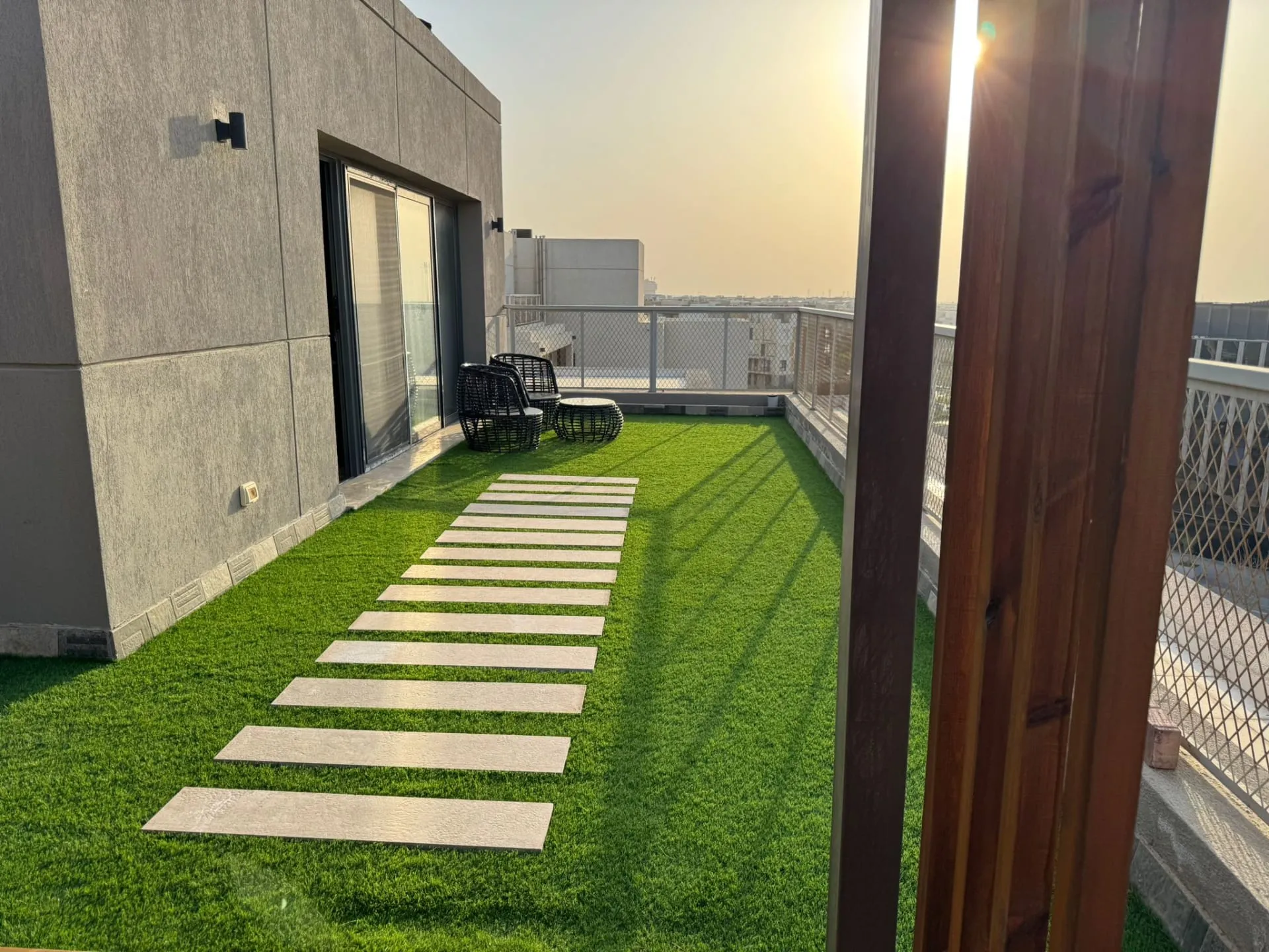 Rooftop terrace with an artificial-grass lawn, stepping-stone path and outdoor chairs at a furnished studio in New Cairo